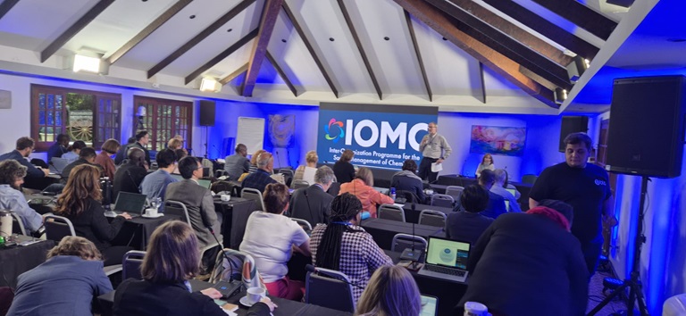 Meeting room with several people with a presentation showing the partnership logo